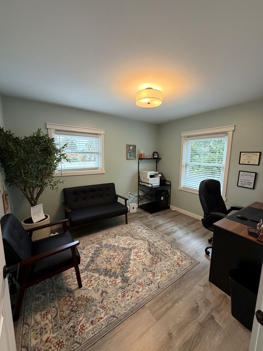 Office with a desk, a small sofa and armchair, and a large plant